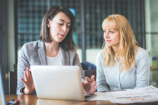 Zwei Geschäftsfrauen Arbeiten Mit Laptop Und Papierkram Café Farbton Effekt lizenzfreie Stockbilder