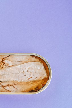 Mor arkaplanda konserve uskumru filetosu.