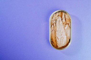 Mor arkaplanda konserve uskumru filetosu.