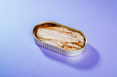 Mor arkaplanda konserve uskumru filetosu.