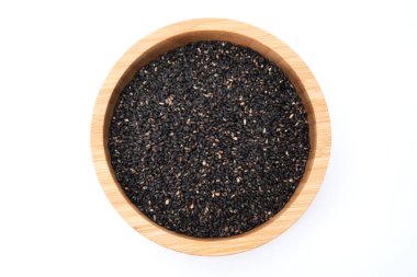 Beyaz arka planda izole edilmiş ahşap kasedeki siyah susam tohumlarının üst görüntüsü
