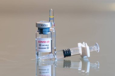 COVID 19 Coronvavirus canlı virüs biyolojik tehlike kültürü şişesi. Önünde bir şırınga, önünde de iğne ucu var. 091.
