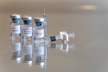 Yakın plan üçlü bir COVID-19 Coronvavirus aşısı seti. Önünde bir şırınga, önünde de iğne ucu var. 107.