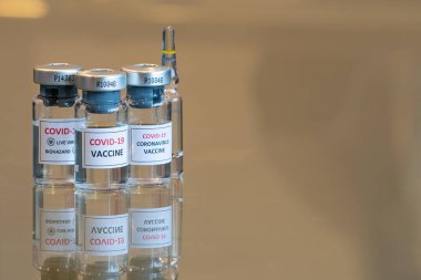 Üç adet COVID-19 aşısı ilaç deney tüpü ve arkasında test ampulü var. 002