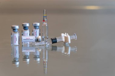 Dört tane küçük COVID-19 Coronvavirus aşısı seti, sağında bir şırınga, arkasında da bir ampul - 135