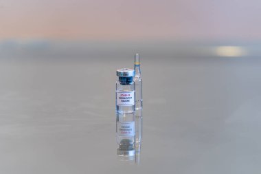 İçinde COVID-19 Coronavirus aşısı olan bir ilaç şişesi ve arkasında da fotokopi alanı olan bir ampul.