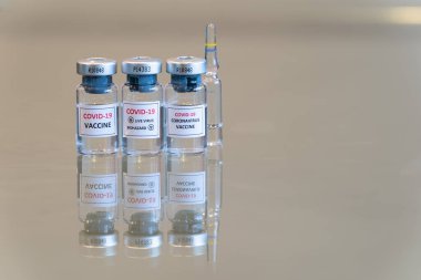 COVID-19 Coronavirus aşılama ilacını içeren yakın çekim üçlü bir şişe seti. Arka tarafında fotokopi alanı olan bir ampul var. 063.