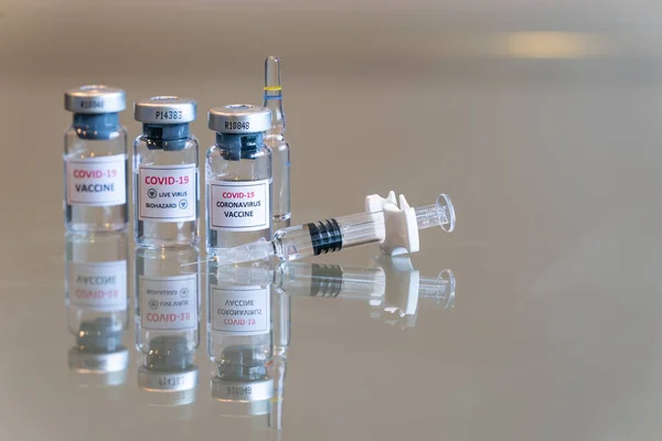 Yakın plan üçlü bir COVID-19 Coronvavirus aşısı seti. Önünde bir şırınga, önünde de iğne ucu var. 107.