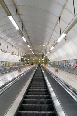 LONDON, ENGLAND - 23 Ekim 2020: Londra Yeraltı yürüyen merdivenleri yoğun saatlerde COVID-19 salgını sırasında yüz maskesi takan bir kadınla Holborn İstasyonu 'nda - 108