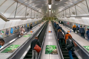 LONDON, ENGLAND - 23 Ekim 2020: Londra Yeraltı yürüyen merdivenleri Holborn Circus istasyonunda yoğun saatlerde yüz maskesi takan ve COVID-19 salgını sırasında sosyal mesafeler belirleyen yolcular - 068
