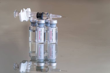 COVID-19 Coronavirus Faz 2 ve Aşama 3 aşısı aşısı olarak etiketlenmiş tıbbi şişelerin yakın görüntüsü. Üzerinde dolu bir şırınga bulunan bir çözelti içeren insan ilaç deneyleri. 025