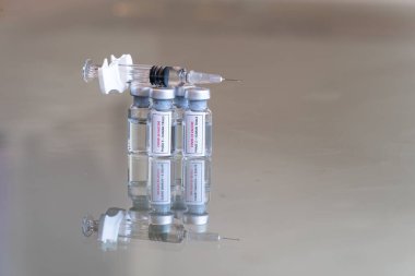 COVID-19 Coronavirus Faz 2 ve Aşama 3 aşısı aşısı olarak etiketlenmiş tıbbi şişelerin yakın görüntüsü. Üzerinde dolu bir şırınga bulunan bir çözelti içeren insan ilaç deneyleri - 026