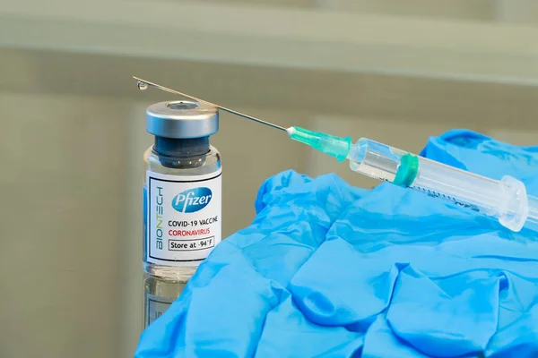 LONDON, ENGLAND - 13 Aralık 2020: Pfizer BioNtec COVID-19 Coronavirus aşı çözeltisi içeren bir cam şişe şırınga enjeksiyonu ve lateks eldivenle kullanıma hazır - 126