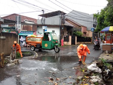 Editoryal Kullanım için, 20 Şubat 2021, PPSU (penanganan prasarana dan sarana umum), Doğu Jakarta, Endonezya 'da sel baskınında küçük bir nehirde turuncu üniforma kullanan iki temizlikçi