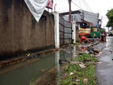 Editoryal Kullanım için, 20 Şubat 2021, PPSU (penanganan prasarana dan sarana umum), Doğu Jakarta, Endonezya 'da sel baskınında küçük bir nehirde turuncu üniforma kullanan iki temizlikçi