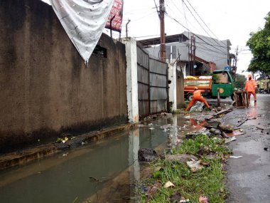 Editoryal Kullanım için, 20 Şubat 2021, PPSU (penanganan prasarana dan sarana umum), Doğu Jakarta, Endonezya 'da sel baskınında küçük bir nehirde turuncu üniforma kullanan iki temizlikçi