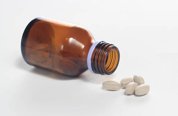 Beyaz arkaplanda şişe vitaminini dök