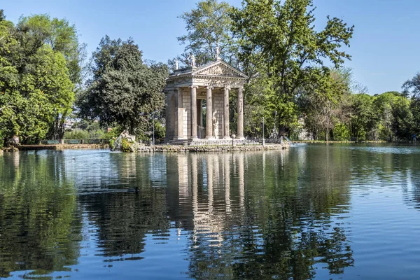Villa Borghese parkındaki suya yansıyan ağaçlarla dolu küçük bir göl.