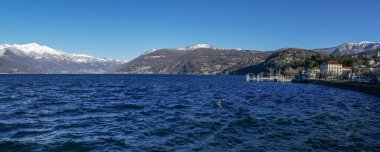 Luino ve Maggiore Gölü 'nün arka planında karla kaplı dağlar var.