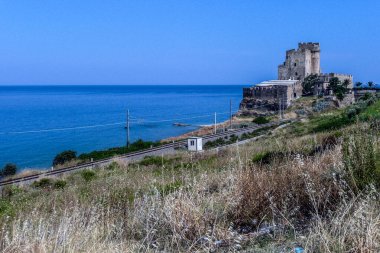 Yeşil denizli Roseto Capo Spulico plajı ve ona bakan şato.