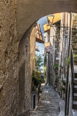 The interior of Corenno Plinio with narrow stone streets, arches and flowers