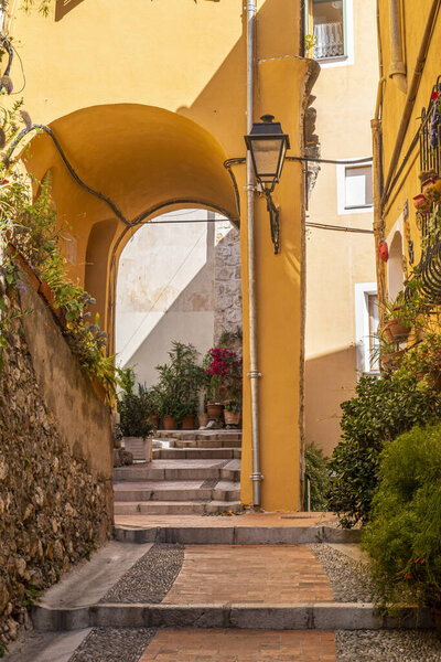 Beautiful street in the old town of Menton with flowers and arches