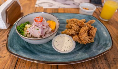 Taze balık, soğan, kırmızı biber, marul, narenciye, kıtır balık ve kremalı sosun yanında servis edilen, rustik stil, canlı lezzet ve zanaatkar sunumlu Peru ceviche..