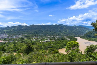 Tingo Mara ve Ro Monzn 'un panoramik şehir manzarası parlak mavi gökyüzünün altındaki yemyeşil dağların yanında. Seyahat, doğa, turizm ve çevre temaları için ideal canlı tropikal manzara.