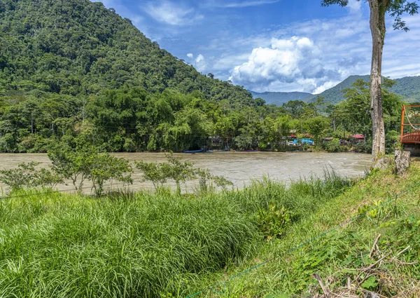 Ro Monzn, Peru Tingo Mara 'da yemyeşil dağların yanında akıyor. Parlak gökyüzü, yoğun bitki örtüsü ve canlı tropikal manzara seyahat, doğa ve açık hava temaları için ideal doğal bir manzara yaratır..