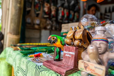 Tingo Mara 'daki bir pazar masasında renkli ahşap oymalar, papağan figürleri ve orman kültürünü ve bölgesel zanaatkarlığı ön plana çıkaran zanaatkarlık içeren el yapımı Peru Amazon el sanatları sergilenmektedir..