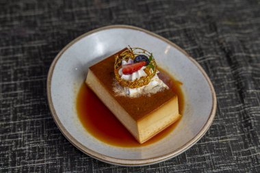 Krem şantili ve taze meyve garnitürlü karamel flan tatlısı. Restoran ve otel tatlı menüleri için zarif bir sunumla gurme kreması..