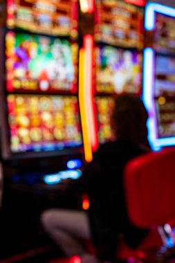 Kumar makineleri ve isimsiz bir oyuncuyla kumarhanenin içini bulanıklaştırmış. Odaksız ışıklar ve ekranlar, gece hayatı, eğlence, eğlence, eğlence, risk ve şans kavramlarıyla soyut bir kumar ortamı yaratır..