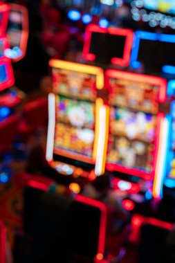 Kumar makineleri ve neon ışıkları olan bulanık bir kumarhane. Renkli ekranlar soyut bir kumar ortamı yaratır. Gece hayatını, eğlenceyi, eğlenceyi, eğlenceyi, şansı ve riski temsil eder..