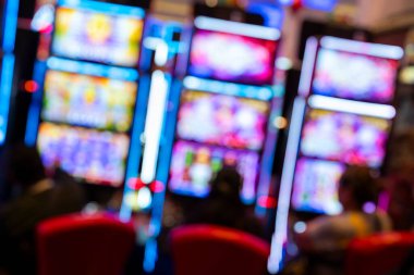 Slot makineleri ve neon ışıkları olan soyut, bulanık bir kumarhane. Renkli ışıltı, gece hayatı, eğlence, eğlence, eğlence, şans ve riskle ilgili canlı bir kumar ortamı yaratır..