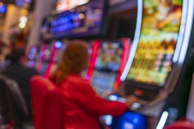 Kumar makineleri, neon ışıkları ve siluetleri olan bulanık bir kumarhane. Renkli ışıltı, gece hayatı, eğlence, eğlence, eğlence, şans ve risk ile bağlantılı soyut bir kumar ortamı yaratır.