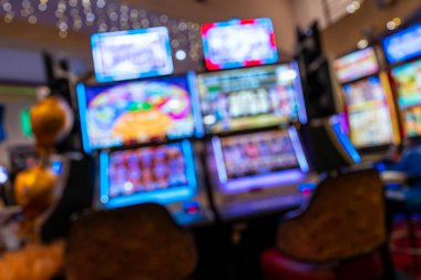 Modern bir kumarhanenin içindeki bulanık slot makineleri renkli ekranlar parlak ışıklar ve sönük ekran gece hayatı eğlencesi havası yaratıyor! Oyun eğlencesi ve kumarhane tecrübesine odaklan.