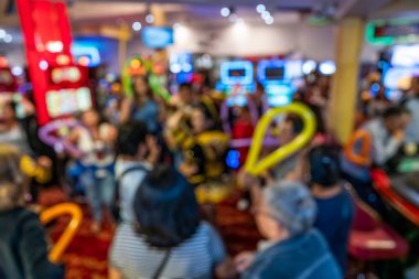 Bir şenlik sırasında kumarhanenin içinde kutlama yapan kalabalık. Renkli balonlar parlak ışıklar ve hareket bulanıklığı eğlence amaçlı gece hayatı ve sosyal kutlama üzerine odaklanmış enerjik bir atmosfer yaratır.