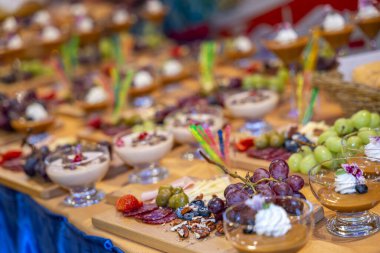 Gurme tatlı masası, tatlı fincanları, taze meyve peyniriyle ve pişirilmiş etle bir yemek organizasyonu için hazırlandı. Lüks konukseverlik ziyafeti hizmeti ve lüks yemek deneyimine odaklanmış şık bir sunum.