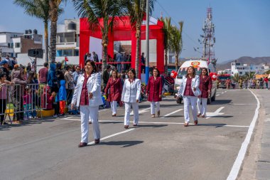 Resmi üniforma giyen kurumsal kadın personel, Peru 'da kamu hizmeti, liderlik, takım çalışması ve kurumsal varlığı temsil eden seyirciler caddeden izlerken sivil bir geçit töreninde birlikte yürürken,.