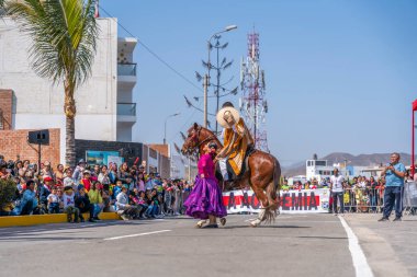 Marinera dansçıları, bir at binicisinin ve renkli kostümlerin yer aldığı bir sivil geçit töreninde geleneksel Peru dansı yapıyorlar. Seyirciler, Peru 'daki folklor, kültür mirası ve ulusal gururu ön plana çıkararak sokaktan izliyor.