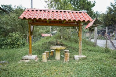 Ahşap masalı ve Peru 'nun kırsal kesiminde ağaçlarla çevrili dışkıları olan kırsal yol kenarı barınağı. Otlar ve yeşillikler açık hava dinlenme ve seyahat yerlerini gösteriyor.