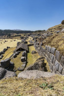Ceremonial temple Sacsayhuaman with Inca stone terraces and walls on hillside archaeological site in Cusco, Peru. Sacred prehispanic architecture representing Andean culture, heritage and ancient engineering under clear blue sky