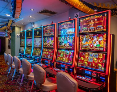 LED ekranlar, renkli grafikler ve aydınlatılmış çerçeveler içeren bir dizi modern kumarhane kumar makinesi. Oturma ve ışıklandırma, eğlence ve kumar temaları için mükemmel bir oyun ortamı yaratıyor..