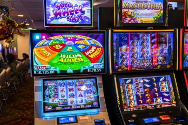 LED ekranlar, renkli grafikler ve aydınlatılmış çerçeveler içeren bir dizi modern kumarhane kumar makinesi. Oturma ve ışıklandırma, eğlence ve kumar temaları için mükemmel bir oyun ortamı yaratıyor..