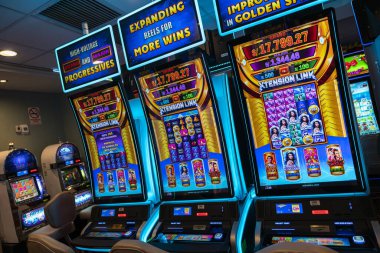 LED ekranlar, renkli grafikler ve aydınlatılmış çerçeveler içeren bir dizi modern kumarhane kumar makinesi. Oturma ve ışıklandırma, eğlence ve kumar temaları için mükemmel bir oyun ortamı yaratıyor..