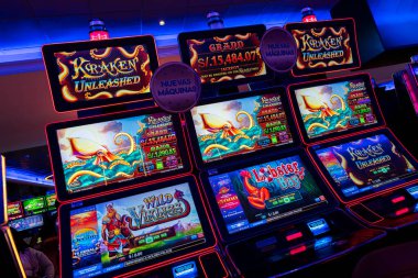 Kumarhanenin içinde renkli ekranları ve parlak neon ışıkları olan bir dizi ışıklı kumar makinesi. Sahnede yastıklı koltuklar, desenli halı ve kumar ve eğlence temaları için ideal canlı elektronik gösteriler yer alıyor..