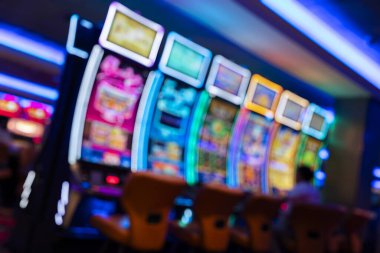 Aydınlatılmış kumar makineleri ve renkli dijital ekranları olan modern bir kumarhanenin iç görünümü. Reklam için ideal eğlence, gece hayatı eğlence, turizm, kumarhane endüstrisi, oyun teknolojisi ve konukseverlik deneyimleri.