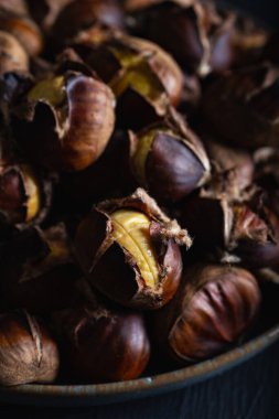 Koyu arkaplanda seramik tabakta kavrulmuş kestane. Kış arkaplanı.