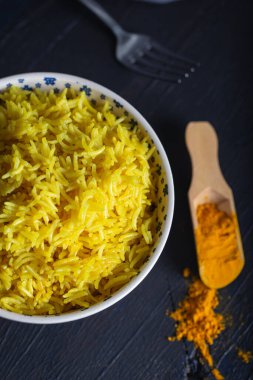 Basmati pilavından yapılan bir kase sarı pirinç ve zerdeçal tozu.