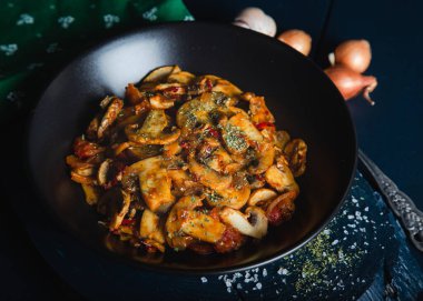 Siyah tabakta bitki ve baharatla pişirilmiş mantar. Mantar sotesi.